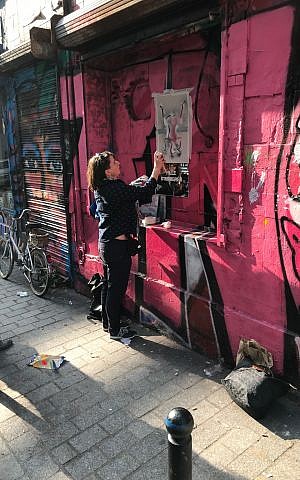 Shiry Avny spraypaints a stencil during her street art demonstration near the end of her tour. (Robert Sarner/ Times of Israel)