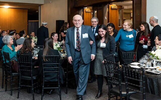 Holocaust survivor Pinchas Gutter enters the main hall together with an attendee at the Dinner of Miracles in Toronto, December 15, 2019.