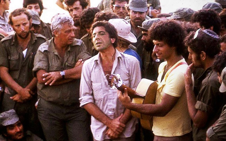 Leonard Cohen, center, performing with Israeli singer Matti Caspi, on guitar, for Ariel Sharon, with arms crossed, and other Israeli troops in the Sinai in 1973. (Courtesy of Maariv via JTA)