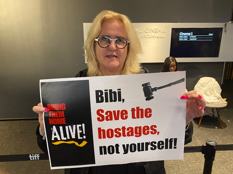 Activist Helene Meyer holds a poster promoting a hostage release deal at the Toronto screening of ‘The Bibi Files’ on September 9, 2024. (Robert Sarner/Times of Israel)
